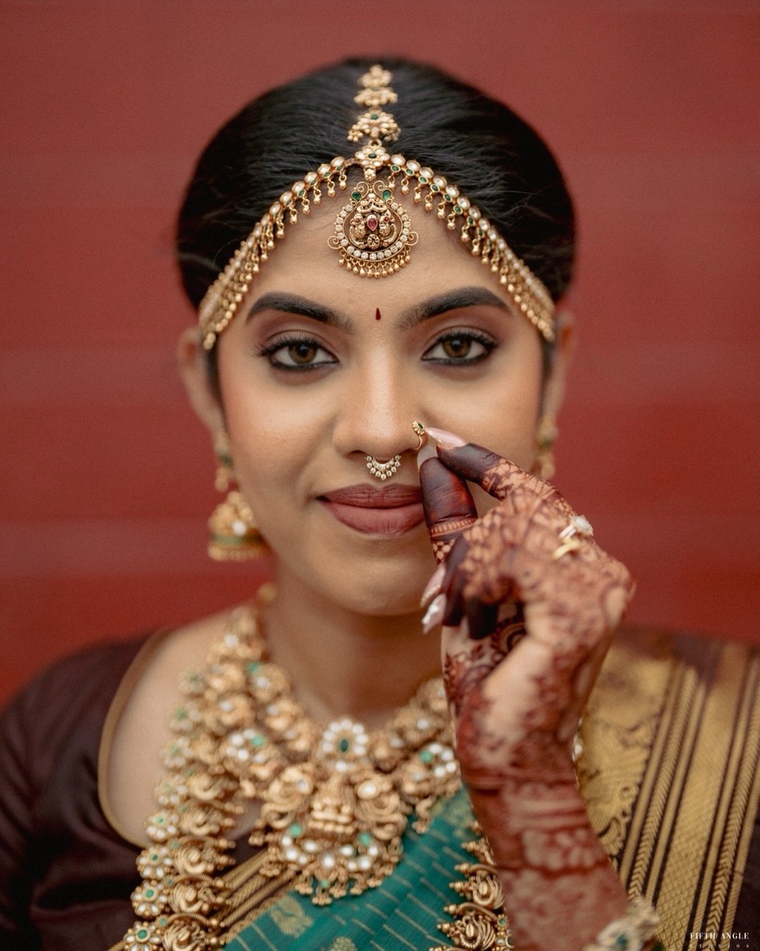 A bride adjusting her traditional nose ring in a close portrait